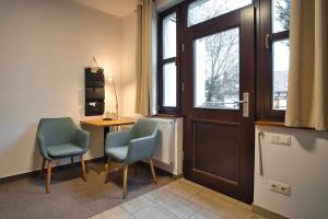 a room with two chairs and a desk and a door at Luisenhof in Neuglobsow