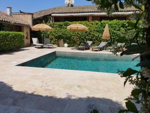 a swimming pool with chairs and umbrellas next to a house at Le Mas de Mougins in Mougins