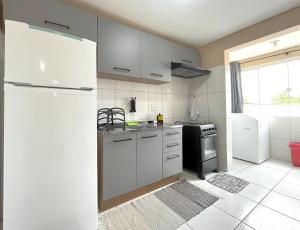 une cuisine avec des armoires blanches et un réfrigérateur dans l'établissement Centro de Barra velha - 550m do Mar, à Barra Velha