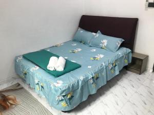 a bed with a blue comforter and two towels at AINUL HOMESTAY in Pasir Mas
