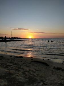 two people swimming in the ocean at sunset at Paille en Queue apartment in Grand Baie