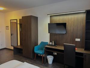 een hotelkamer met een bureau en een tv bij Ayhan Hotel in Burgdorf