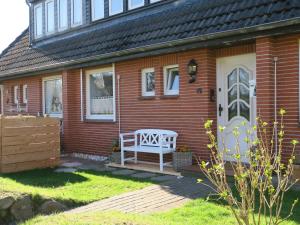 une maison avec un banc blanc sur la terrasse couverte à l'avant dans l'établissement Ferienhaus Süder-Tresker, à Tinnum