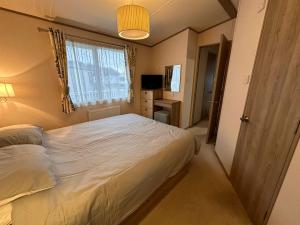 Un dormitorio con una gran cama blanca y una ventana en Tattershall Lakes 6 berth with bath, en Tattershall