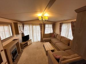 a living room with a couch and a tv at Tattershall Lakes 6 berth with bath in Tattershall