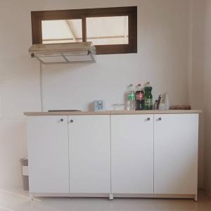 a white kitchen with white cabinets and a window at ฺBaannoi in the garden บ้านน้อยกลางทุ่ง Pool villa 