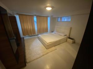 een kleine slaapkamer met een wit bed en ramen bij Luka Central Apartment in Craiova