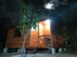 una piccola casa in legno con un albero di fronte di Aura Bungalow a Tamarindo