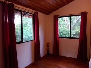 2 Fenster in einem Zimmer mit roten Vorhängen in der Unterkunft Aura Bungalow in Tamarindo