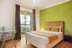 um quarto com uma cama, uma secretária e uma janela em Apartamento Caires no Funchal