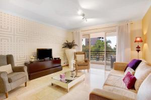uma sala de estar com um sofá e cadeiras e uma televisão em Apartamento Caires no Funchal