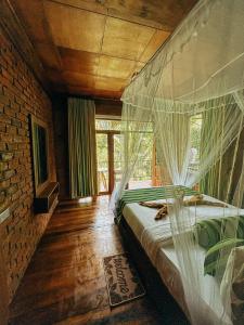 a bedroom with a bed with mosquito nets on it at NatureWoodland in Ella