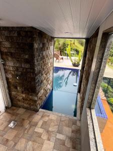 una piscina en una casa con una pared de piedra en Suíte em Miguel Pereira, en Miguel Pereira