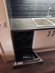 eine leere Spülmaschine in einer Küche unter einer Spüle in der Unterkunft Family Apartaments in Sarandë