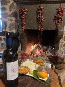 a bottle of wine and a plate of food and a fireplace at Kulla Hupi Agriturism in Bulqizë