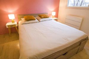 une chambre avec un grand lit blanc avec deux lampes dans l'établissement Appartement cosy, à Thonon-les-Bains