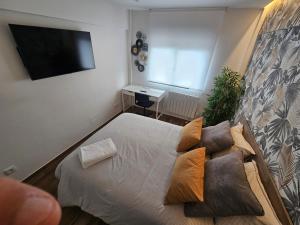 a bedroom with a bed with pillows and a flat screen tv at apartamento a estrenar junto al Sardinero in Santander