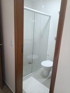 een badkamer met een toilet en een glazen douche bij Hotel Mãe Peregrina in Aparecida