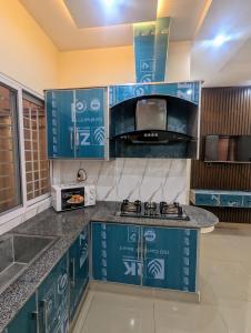 a kitchen with blue cabinets and a microwave at Executive Apartments in Gujrānwāla