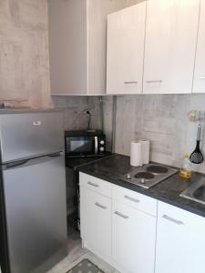uma cozinha com armários brancos e um frigorífico de aço inoxidável em PALMA II em Port-la-Nouvelle
