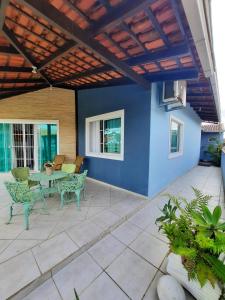 a patio with a table and chairs and a blue wall at casa no paraíso do Capri in São Francisco do Sul