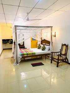 1 dormitorio con 1 cama con dosel y 2 sillas en Riparian Ahangama, en Ahangama