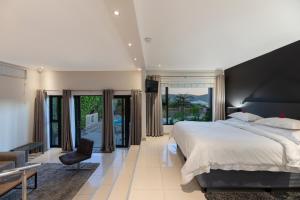 THEBLOEM Guest Suites by Knysna Paradise Collection في كنيسنا: غرفة نوم بسرير كبير ونوافذ كبيرة