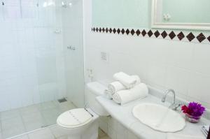 a white bathroom with a toilet and a sink at Guest House Green Garden in Búzios