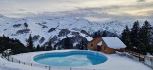 a building with a swimming pool in the snow at Le Chaleureux Cocon Rouge in Ustou