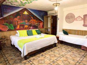 Cette chambre comprend deux lits et un tableau mural. dans l'établissement Eco Hotel El Refugio de La Floresta, à Leticia