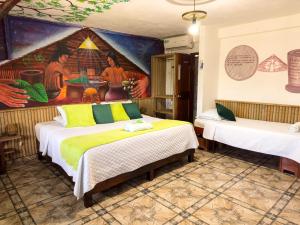 a room with two beds and a painting on the wall at Eco Hotel El Refugio de La Floresta in Leticia