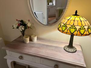 una lampada seduta su un tavolo con uno specchio di WEE SUZIE STAYS - Stunning George St Apartment a Perth