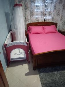 Schlafzimmer mit einem Bett mit rosa Bettwäsche und einem Vorhang in der Unterkunft Appartement idéal Riad Al salam à 8 minutes de la plage du centre ville,Wifi et parking gratuits in Agadir