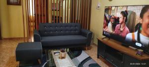 ein Wohnzimmer mit einem Sofa und einem TV in der Unterkunft HOMESTAY ALORSETAR TOWNCENTRE by ASTARILA GUESTHOUSE-StadiumDarulaman - iSLAM SAHAJA - Private Pool, BBQ Zone & Kolam Pancing Puyu - 8-13pax in Alor Setar