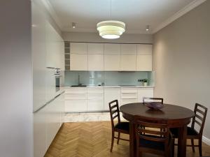 a kitchen with a table and chairs and a kitchen with white cabinets at Apartament Wólczańska w stylu nowojorskim in Łódź