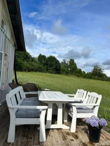 three white chairs and a table on a porch at Gezellig huisje met mooi uitzicht in Holmestrand