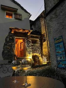 two wine glasses sitting on a table in front of a building at Cà d’la Giannina • local experience Valle Antrona in Pallanzeno