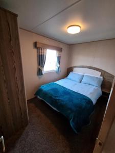 een slaapkamer met een groot bed en een raam bij Primrose Valley Time and Tide Holiday Lets in Filey