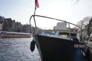 a boat is docked on a river with other boats at Join boathotel in Amsterdam