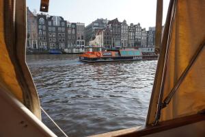 a boat on a river with buildings in the background at Join boathotel in Amsterdam