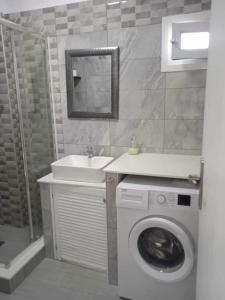 a bathroom with a washing machine and a sink at Kalymnos Platy Gialos Mousellis Makis Apartments in Kalymnos