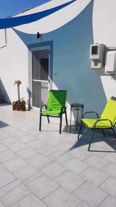 - 2 chaises vertes et une table sur la terrasse dans l'établissement Kalymnos Platy Gialos Mousellis Makis Apartments, à Kalymnos