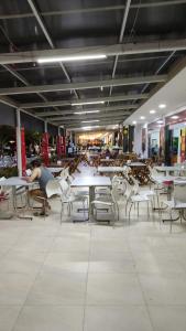 een persoon aan tafels en stoelen in een gebouw bij AP 2 Quartos 6 Pessoas Luxo 200mt Axé Moi in Porto Seguro