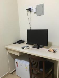 a desk with a computer monitor on top of it at Hotel 5 minutos da Agrishow in Ribeirão Preto