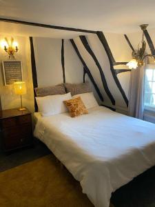 a bedroom with a large white bed with a wooden headboard at Quirky 18th Century Thatched Cottage in Great Staughton