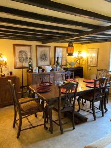 a dining room with a wooden table and chairs at Quirky 18th Century Thatched Cottage in Great Staughton