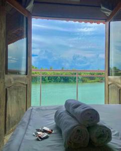 a bed with two rolled up towels and a view of a river at Hotel Beira Rio Preguiças in Barreirinhas