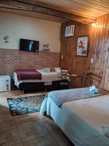 a hotel room with two beds and a table at Pousada Marambaia Café in Barra de Guaratiba