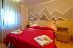 a bedroom with a red bed with towels on it at Hotel Park Oasi in Arta Terme