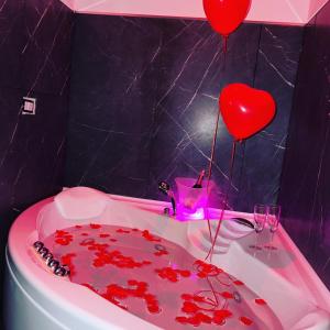 bañera llena de corazones rojos y 2 copas de vino en Altopiano Rooms en Foggia